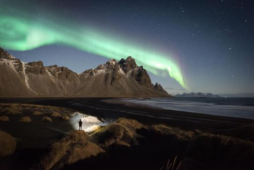 a person standing on a beach under the northern lights at Lilja Guesthouse in Höfn