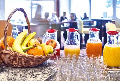 a basket of fruit and bottles of orange juice at Hotel Strandidyll in Grömitz