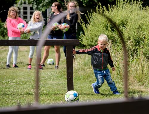 a young boy playing with a soccer ball in the yard at Adventure Park Apartments in Ringkøbing