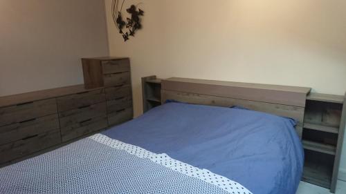 una camera da letto con letto con lenzuola blu e mobili in legno di Maison ocelandes a Saint-Julien-en-Born