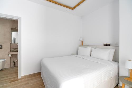 a white bedroom with a white bed and a mirror at Cape Mykonos in Mýkonos City