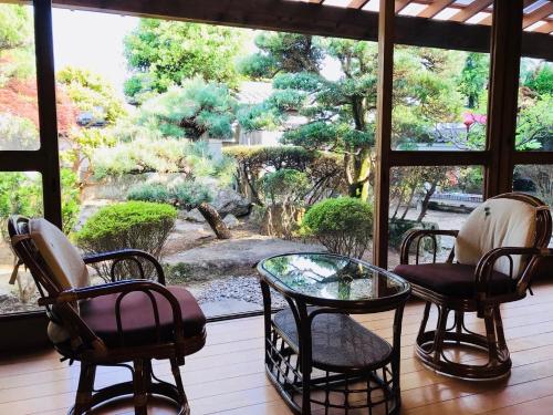 熊野市にあるゲストハウスわがらん家 海の椅子、ガラステーブル、窓が備わる客室です。