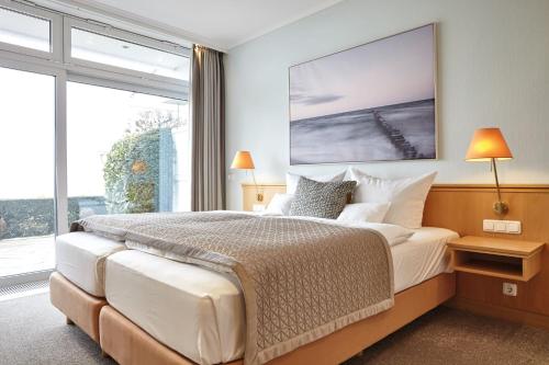 a bedroom with a large bed and a large window at Hotel Strandidyll in Grömitz
