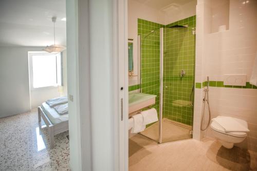 ein Bad mit einer Dusche, einem WC und grünen Fliesen in der Unterkunft Prà de la Fam B&B in Tignale