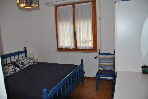 プリンチピナ・ア・マーレにあるCasina Enzaのベッドルーム1室(青いベッド1台、窓、椅子付)