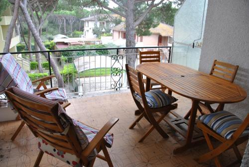 un portico con tavolo e sedie in legno sul balcone di Casina Enza a Principina a Mare