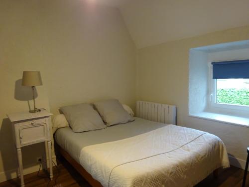 une petite chambre avec un lit et une fenêtre dans l'établissement La Cour du Bourg, à Saint-Jean-des-Champs