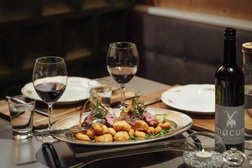 a table with a plate of food and wine glasses at Hotel Macun, Vent im Ötztal in Vent