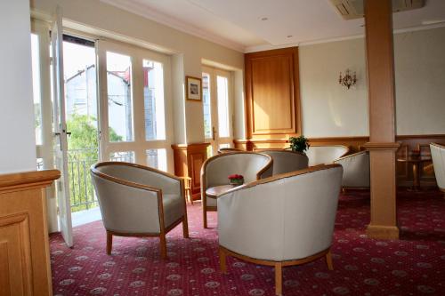a waiting room with chairs and tables and windows at Hôtel Sainte Marie in Lourdes
