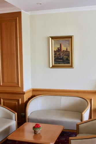 a room with a bench and a table and a picture at Hôtel Sainte Marie in Lourdes