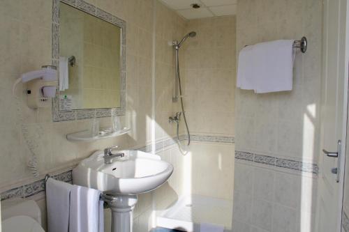 a bathroom with a sink and a mirror and a shower at Hôtel Sainte Marie in Lourdes