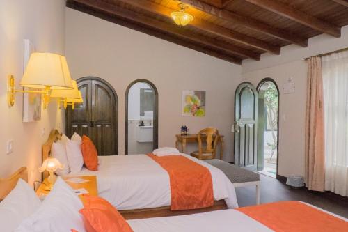 ein Schlafzimmer mit zwei Betten mit orange-weißer Bettwäsche in der Unterkunft La Coupole Hotel in Quito