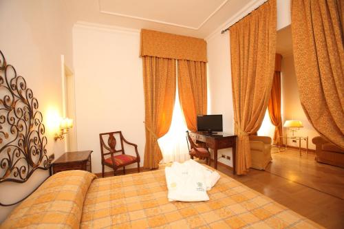 ein Hotelzimmer mit einem Bett, einem Schreibtisch und Vorhängen in der Unterkunft Grand Hotel Villa Balbi in Sestri Levante
