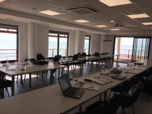a large room with tables and chairs with a laptop at Hotel Les Dunes in La Tranche-sur-Mer
