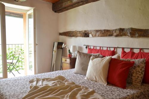 una camera da letto con un letto con cuscini rossi e bianchi di Casa la Finestra sul Lago - WelcHome a Cannobio