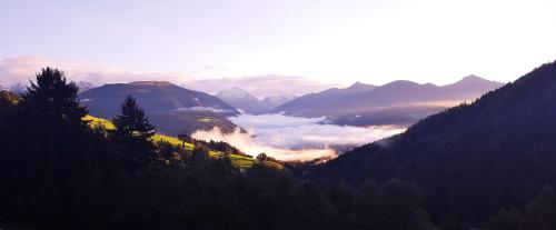 a view of a valley with clouds in the mountains at Residenz Erschbaum in Valdaora