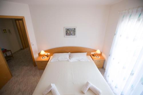 Susanna Apartments في كيراموتي: غرفة نوم بسرير ابيض مع وسادتين بيض