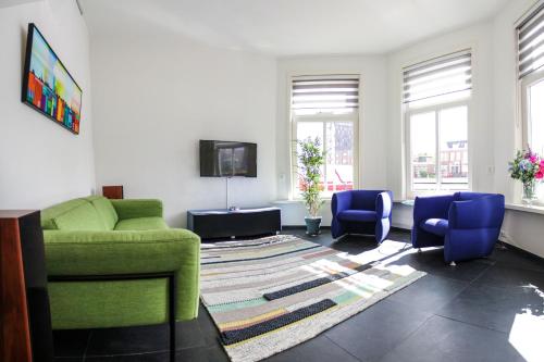 a living room with a green couch and two blue chairs at Skipper 4 - 3 bedroom authentic detached house in City Center in Groningen
