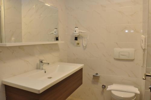 Baño blanco con lavabo y aseo en Sunway club otel, en Marmaris