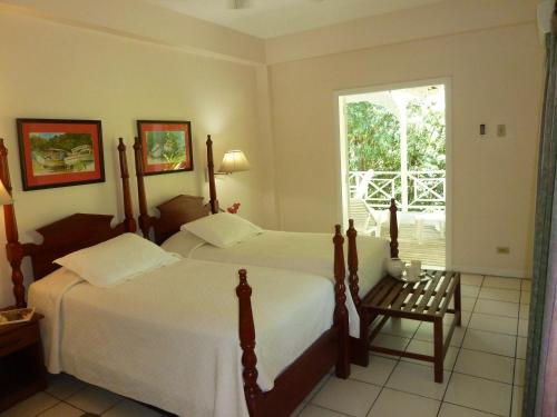 two beds in a hotel room with a window at Plantation Beach Villas in Black Rock