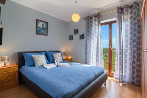 a bedroom with a blue bed and a large window at House Silvija Pula in Šikići