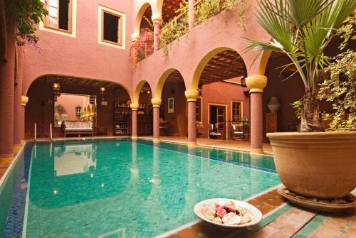 a swimming pool with a bowl of food next to a building at Riad Noga in Marrakesh