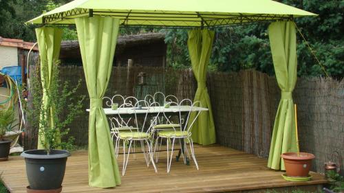 a table and chairs under a green canopy on a deck at Le gite de la Lombriere in Saint-Denis-de-Pile