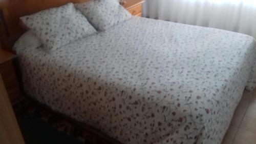 a bed with a white comforter and two pillows at Pension Catro Ventos in Camariñas