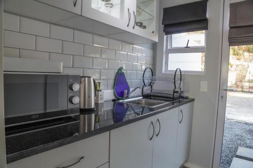 a kitchen with a sink and a microwave at De La Hilcremat in Simonʼs Town