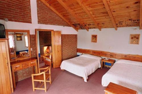 a bedroom with two beds and a desk and a television at Hotel Bella Vista in Huasca de Ocampo