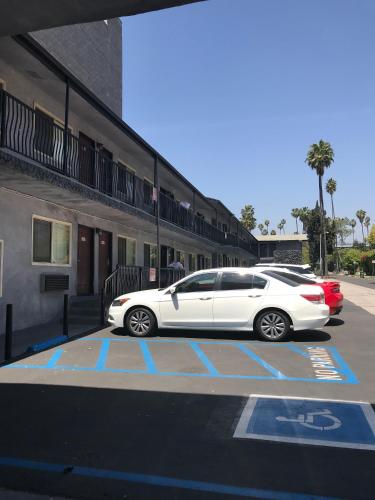 a white car parked in a parking lot next to a building at Hollywood Palms Inns & Suites in Los Angeles