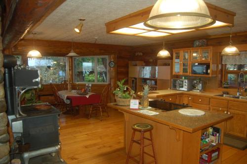 Union Bay Log Home في Union Bay: مطبخ بدولاب خشبي وجزيرة مطبخ مع موقد