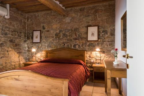 a bedroom with a bed and a stone wall at Il Chiostro Appartamenti & Suites in Suvereto