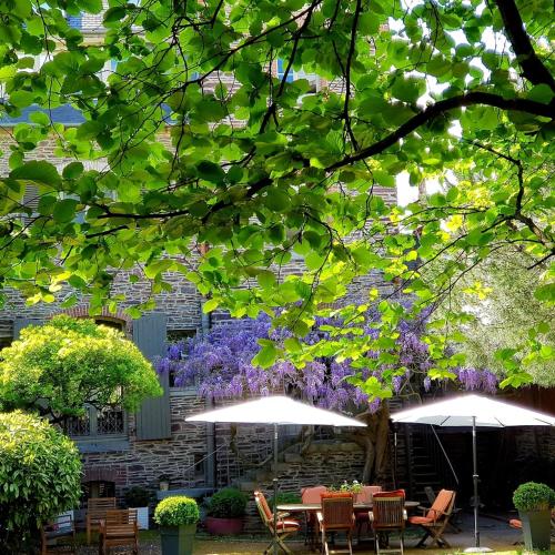 two tables and umbrellas in front of a building with purple flowers at Castel Jolly in Rennes