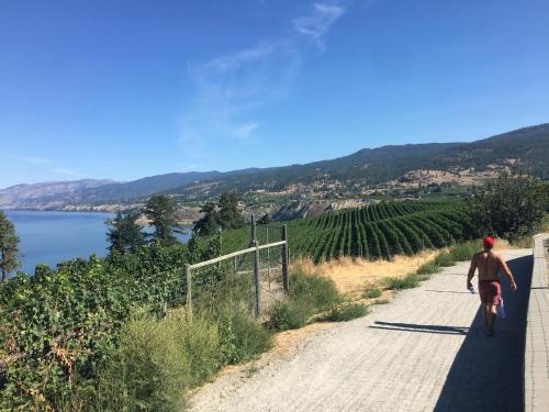 a man riding a bike down a road next to a lake at Black Sea Motel in Penticton