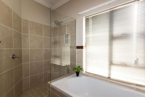 Un baño con bañera y una ventana con una planta. en Serendipity Place, en Plettenberg Bay