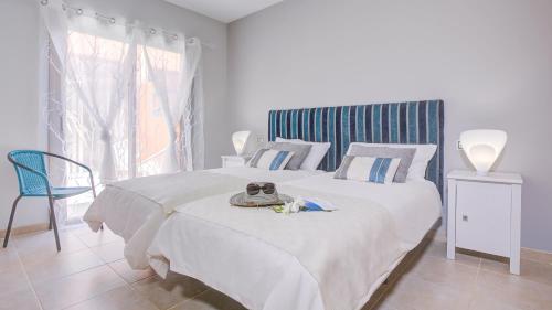 a bedroom with a large white bed with a blue headboard at Villa Del Corazon Salinas Golf in Caleta De Fuste