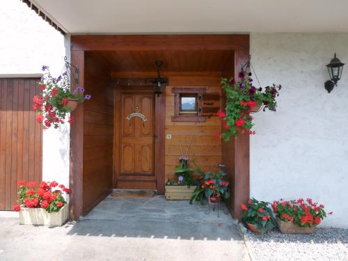 une porte d'entrée d'une maison ornée de fleurs en pots dans l'établissement Chalet coup de coeur, à Passy