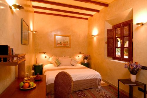 Un dormitorio con una cama y una mesa con un bol de fruta en Riad Noga, en Marrakech