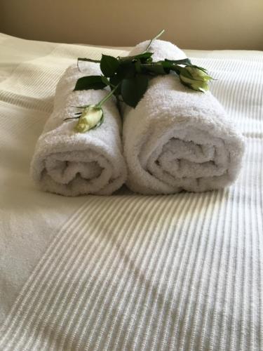 a towel with a flower on top of a bed at Soós Apartman in Balatonfüred