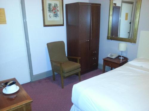 a hotel room with a bed and a chair and a mirror at Tree Hotel at Iffley in Oxford