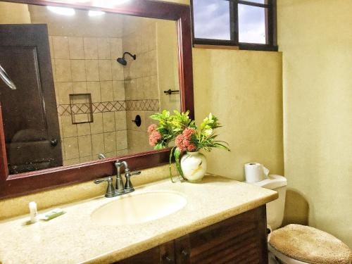 a bathroom with a sink and a toilet with a mirror at Casa Carolina Gran Pacífica Resort in San Diego