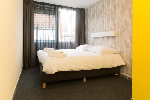 1 dormitorio con 1 cama con 2 toallas en Beach Hotel Katwijk, en Katwijk