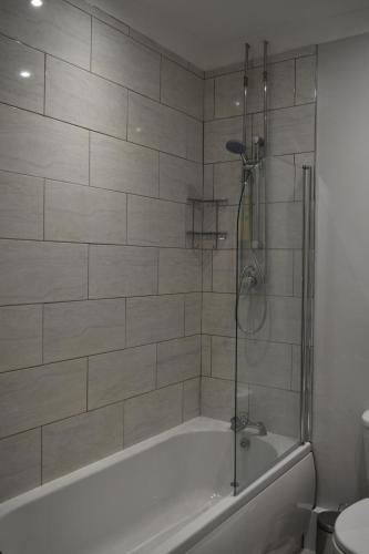 a bathroom with a bath tub with a shower at Adelaide Apartments in Blackpool