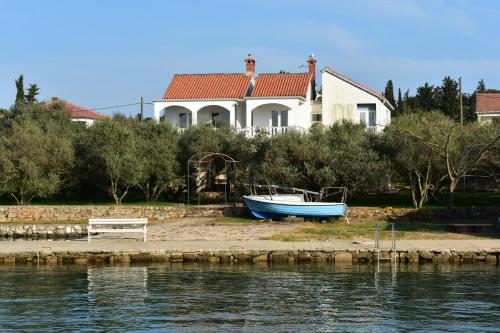 una casa con un barco en la orilla junto al agua en Family House Rebeka en Ugljan