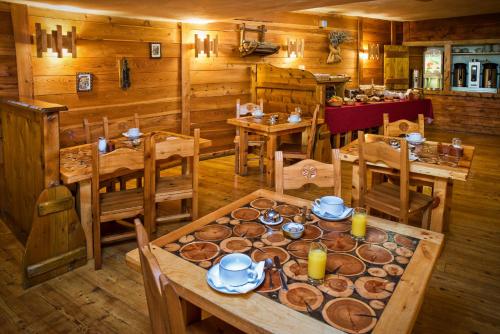 une salle à manger avec des tables et des chaises en bois et de la nourriture dans l'établissement Hôtel & Spa La Ferme de l'Izoard, à Arvieux