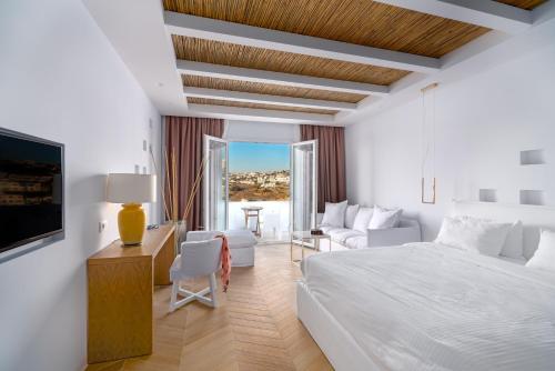 a white bedroom with a bed and a desk and a couch at Cape Mykonos in Mýkonos City