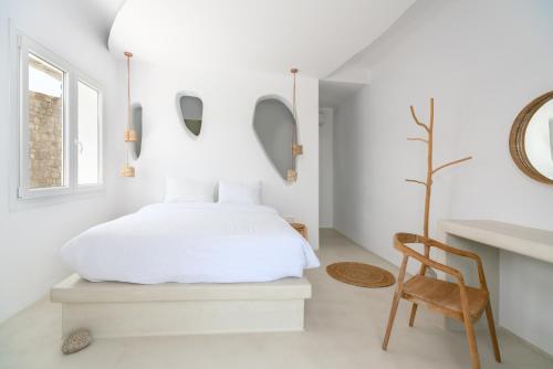 a bedroom with a white bed and a wooden chair at Cape Mykonos in Mýkonos City