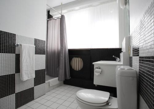 a black and white bathroom with a toilet and a window at Hotel La Royale in Leuven