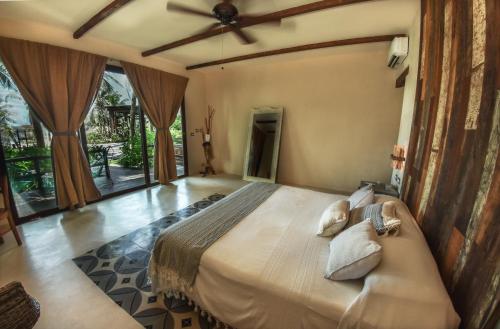 a bedroom with a large bed with a ceiling fan at Maria Del Mar Tulum - Adults Only in Tulum
